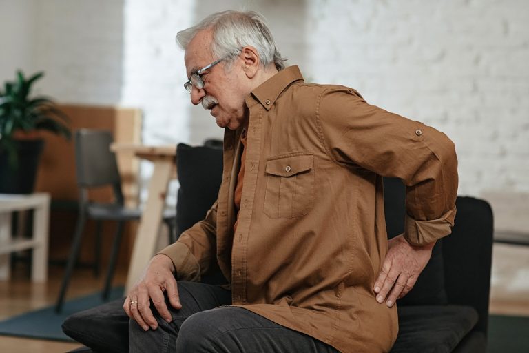 Senior hombre en busca de consejos para el dolor de espalda
